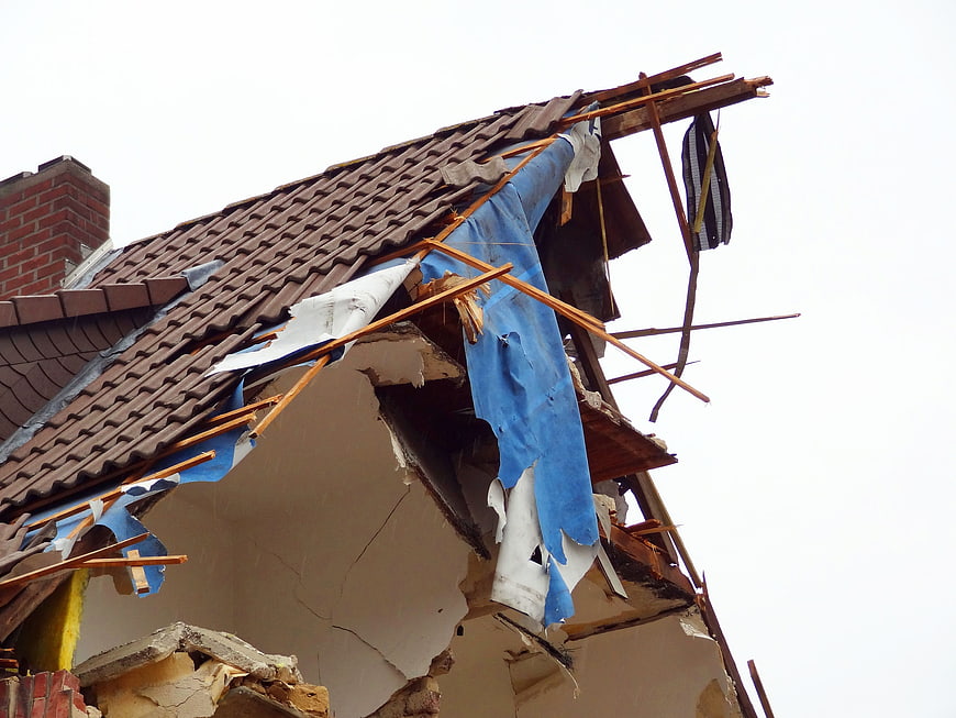 Damaged Residential House Roof With Exposed Insulation And Broken Tiles