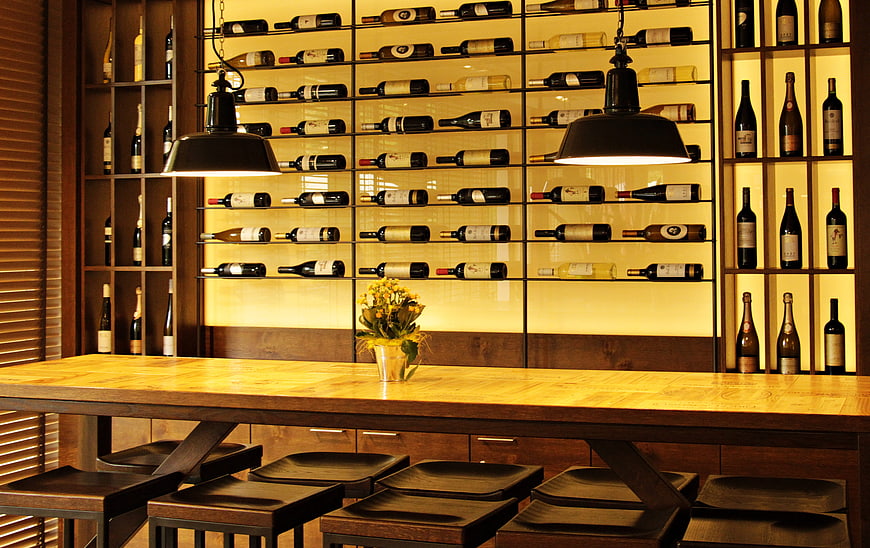 Warmly lit wine bar interior with wooden counter and bottle display