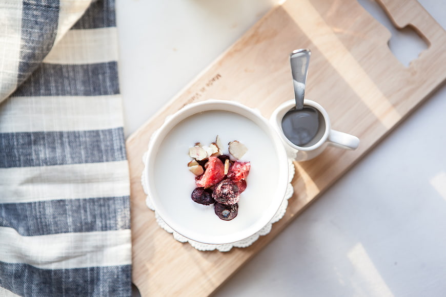 Overhead view of yogurt bowl with berries and nuts on wooden board