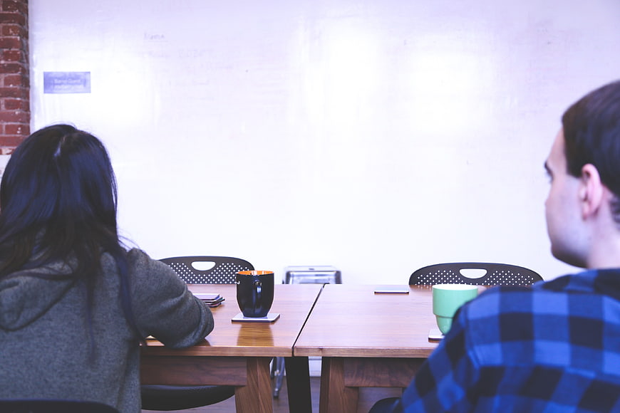 Two people in casual startup meeting facing whiteboard
