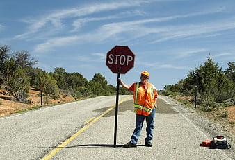 Road worker holding stop sign on rural highway