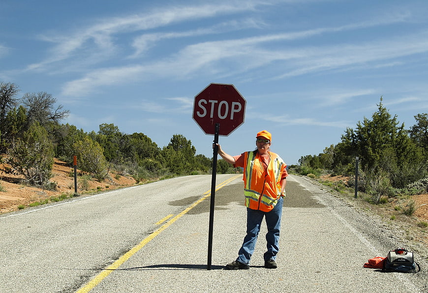 Road worker holding stop sign on rural highway
