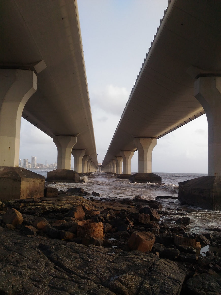 Low angle view under concrete bridge pillars by rocky shore
