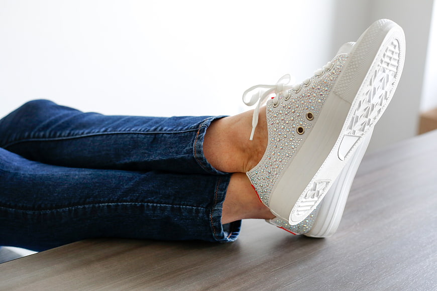 Relaxed feet in sparkly white sneakers on a desk