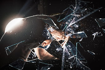 Man breaking through glass in dark dramatic lighting
