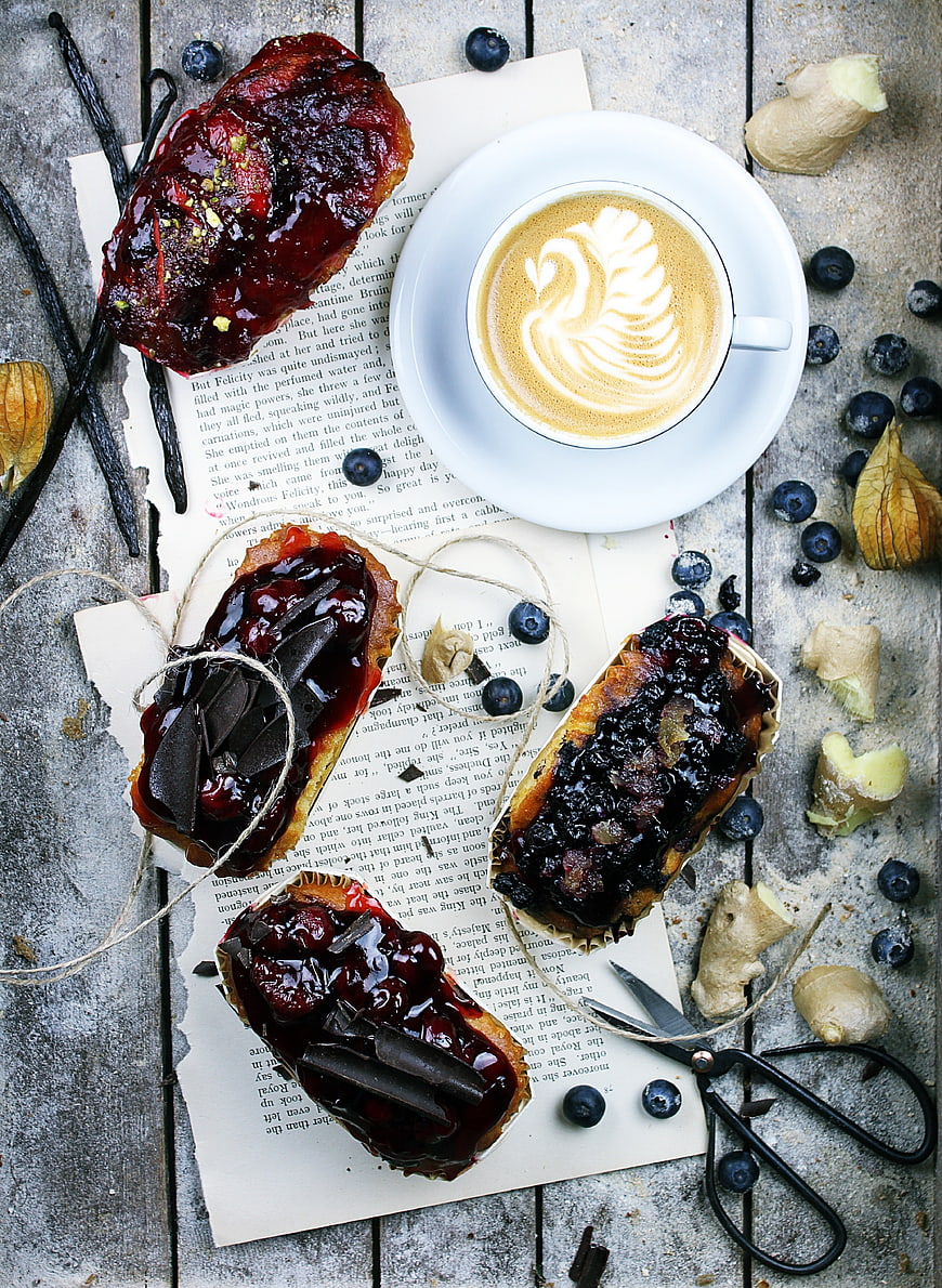 Flat lay of chocolate blueberry pastries and latte art on rustic wood
