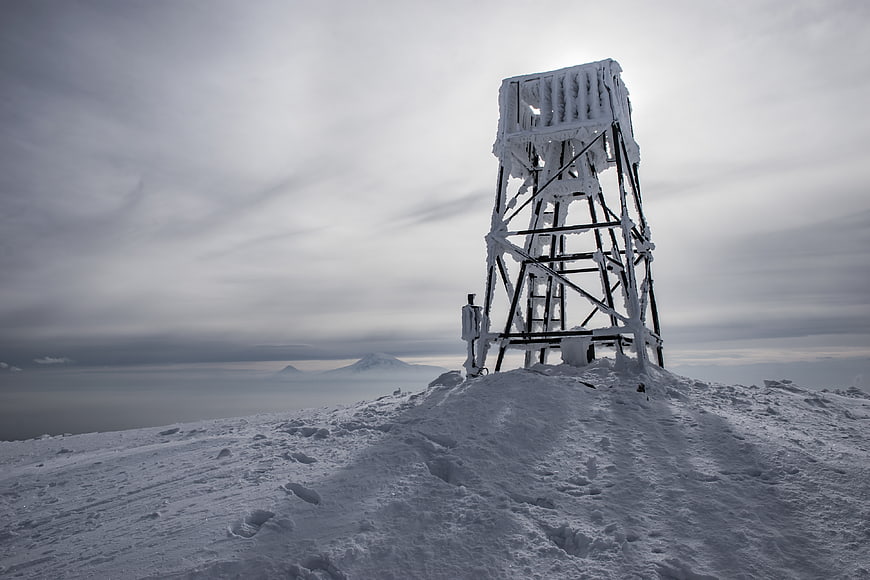 Snow-covered fire lookout tower on mountain peak