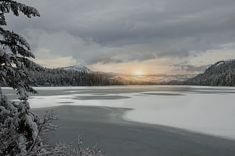 Serene Frozen Lake Landscape with Snowy Forest and Sunset