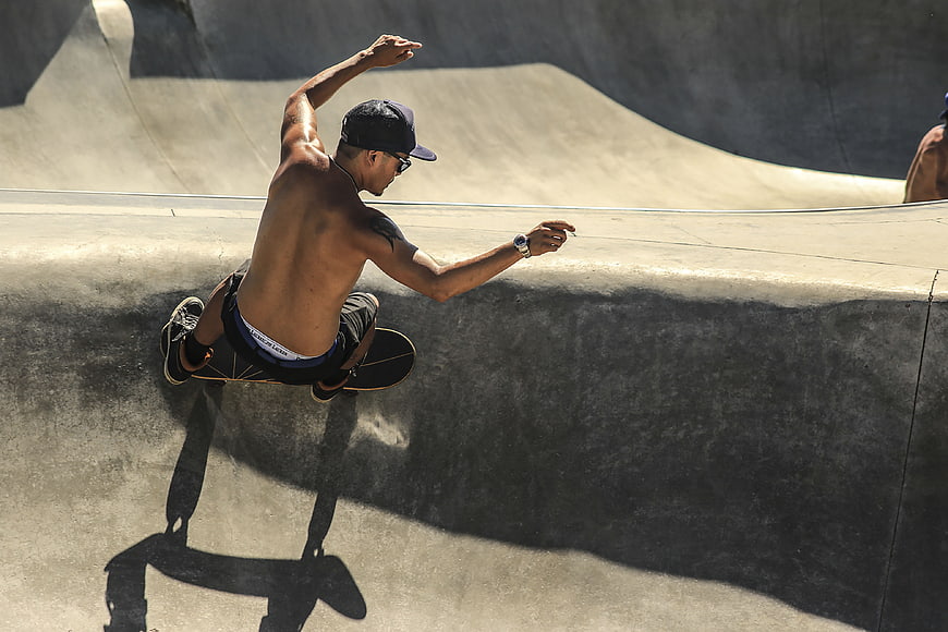 Shirtless Skateboarder Performing Trick in Concrete Skatepark