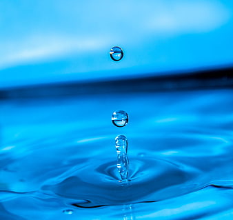 Macro shot of water droplets splashing into blue liquid