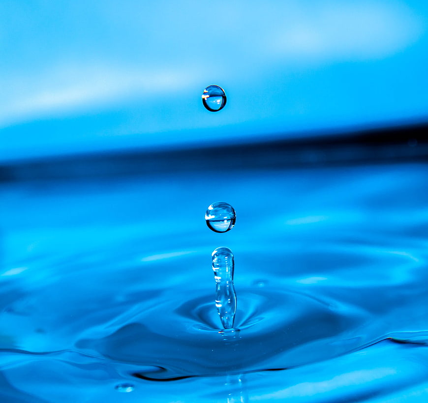 Macro shot of water droplets splashing into blue liquid