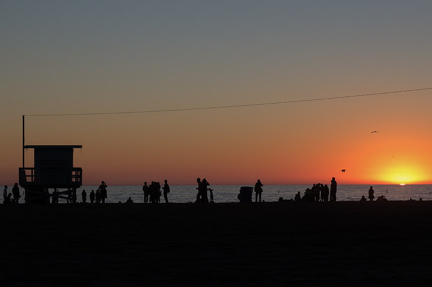 Silhouettes of People on Beach at Sunset with Lifeguard Tower