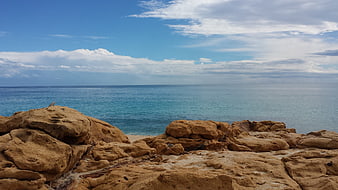 Rugged coastal rocks overlooking turquoise ocean and blue sky