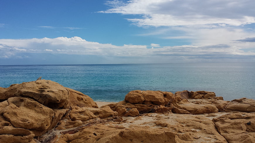 Rugged coastal rocks overlooking turquoise ocean and blue sky