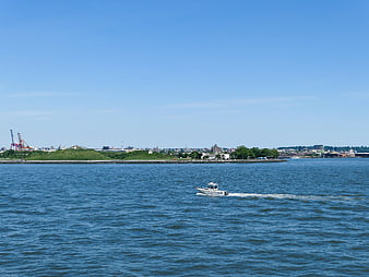 White boat cruising on blue water with city skyline background
