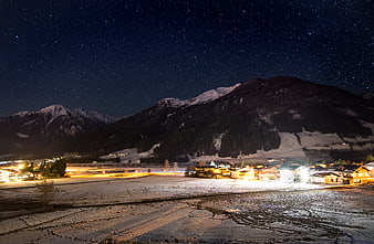 Starry night over snowy alpine village with illuminated chalets