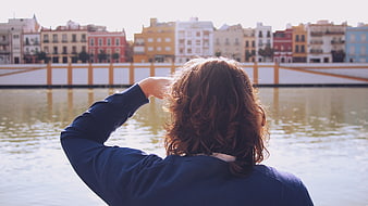 Woman Looking at Seville Cityscape from River