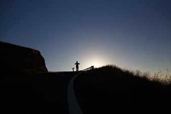 Silhouette of Hiker on Winding Mountain Road at Sunset