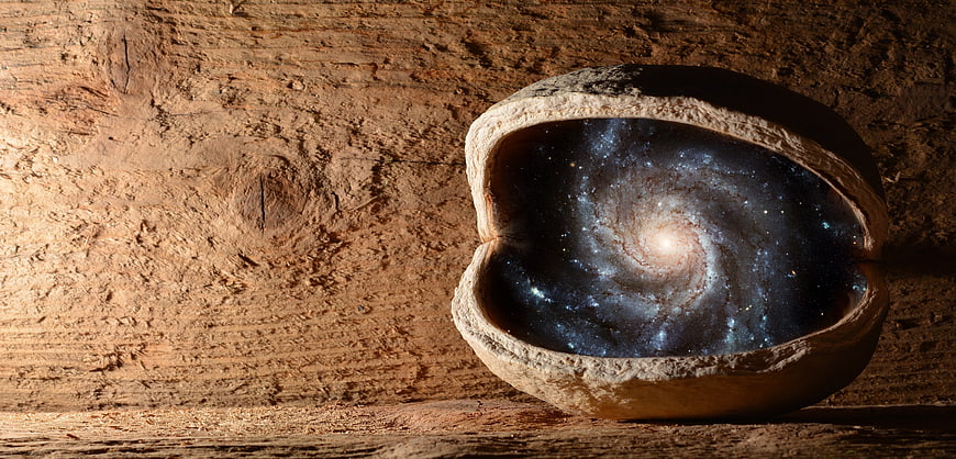 Walnut shell containing a spiral galaxy on rustic wood background