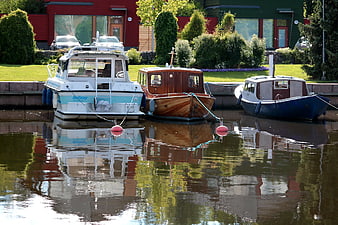 Three boats docked in a canal with reflections