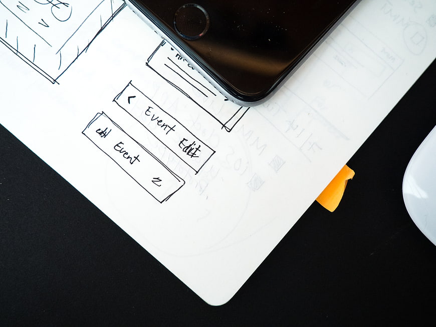 Hand-drawn mobile app wireframe sketch on paper with smartphone