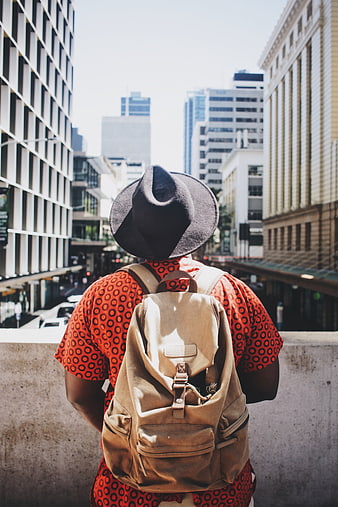 Man with Backpack and Hat Looking at City Skyline