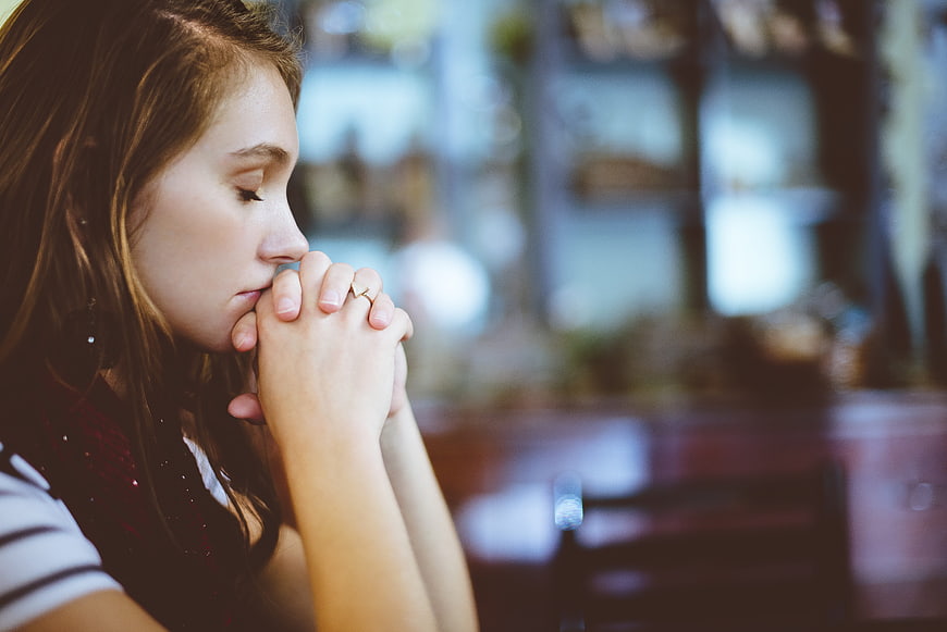 Close-up of young woman praying with hands clasped