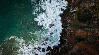 Aerial View of Turquoise Waves Crashing Against Rocky Coastline