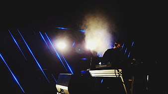 DJ performing at night with blue laser lights and smoke