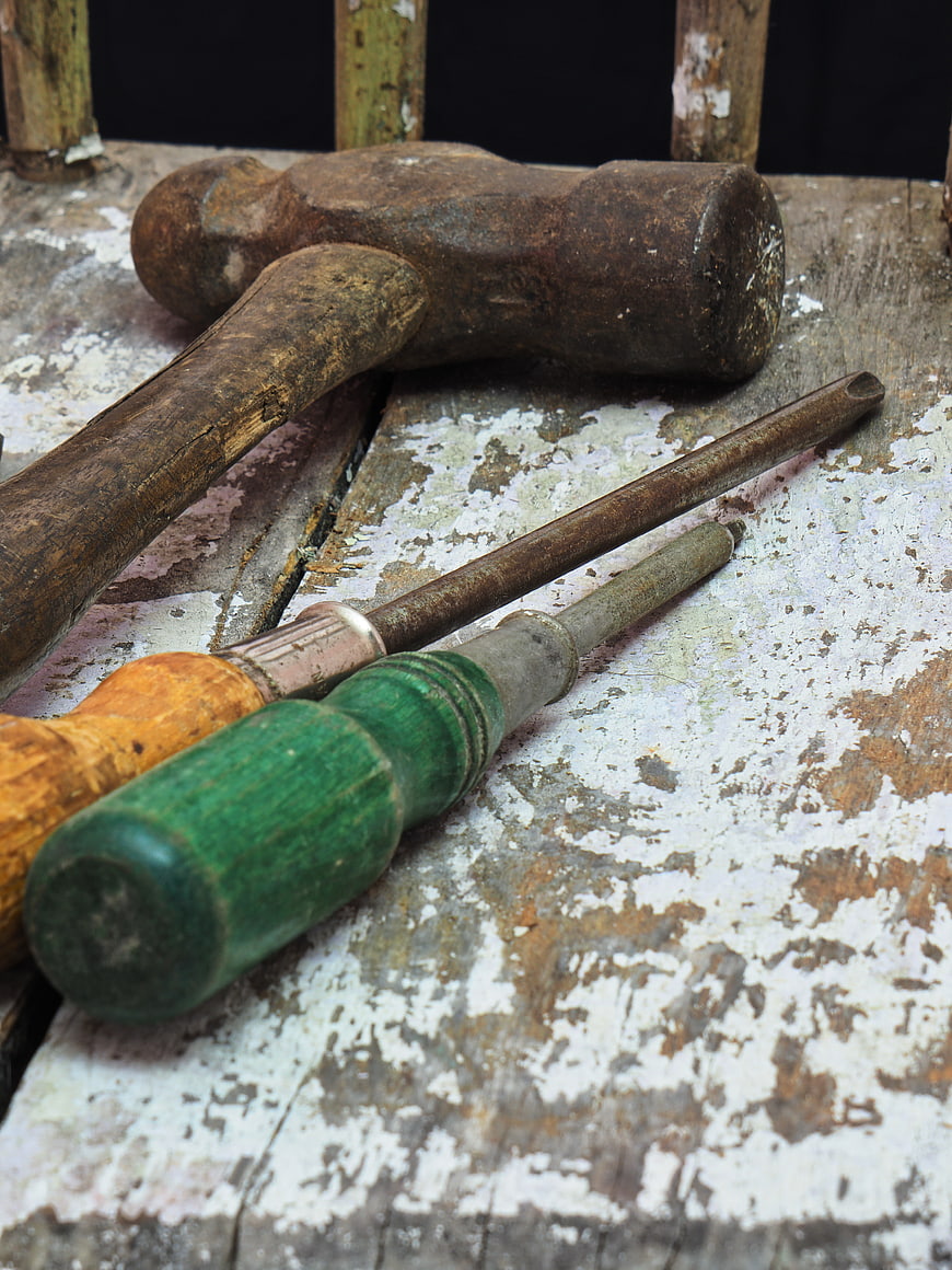 Vintage rusty hammer and screwdrivers on distressed wooden table