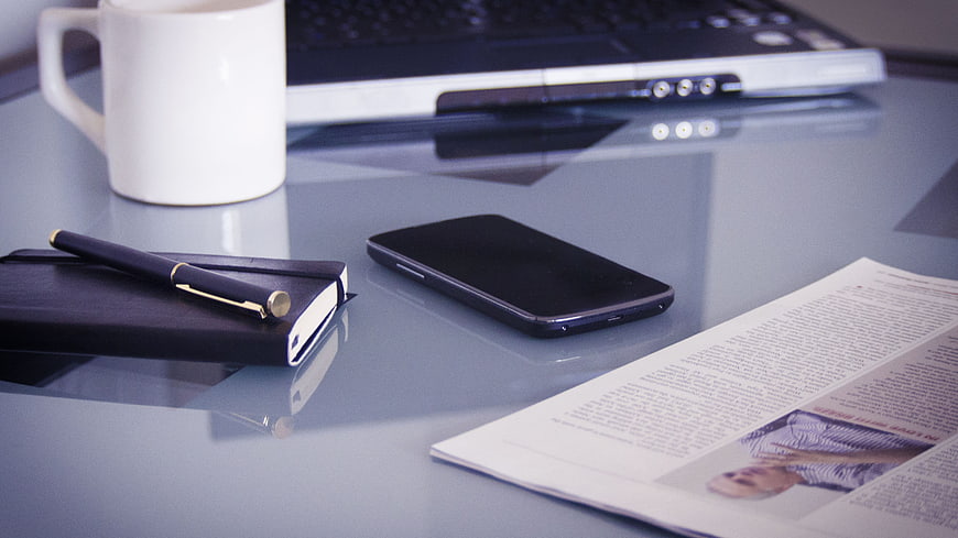 Modern Office Desk Setup With Laptop, Smartphone, Notebook, Pen, And Coffee
