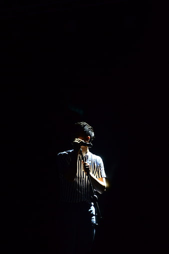 Male Singer Performing on Dark Stage with Spotlight