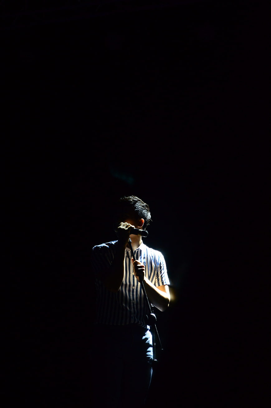 Male Singer Performing on Dark Stage with Spotlight