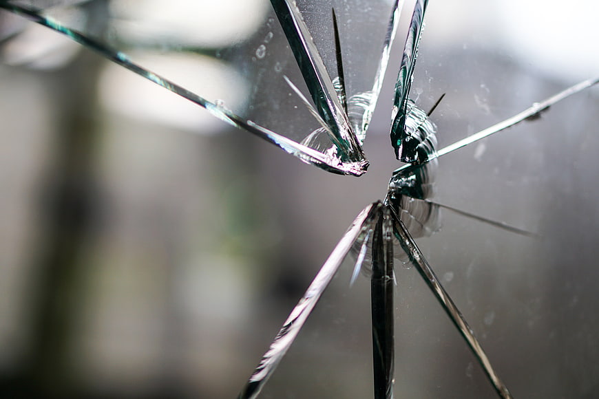 Close-up of shattered glass with radial cracks and splintered edges