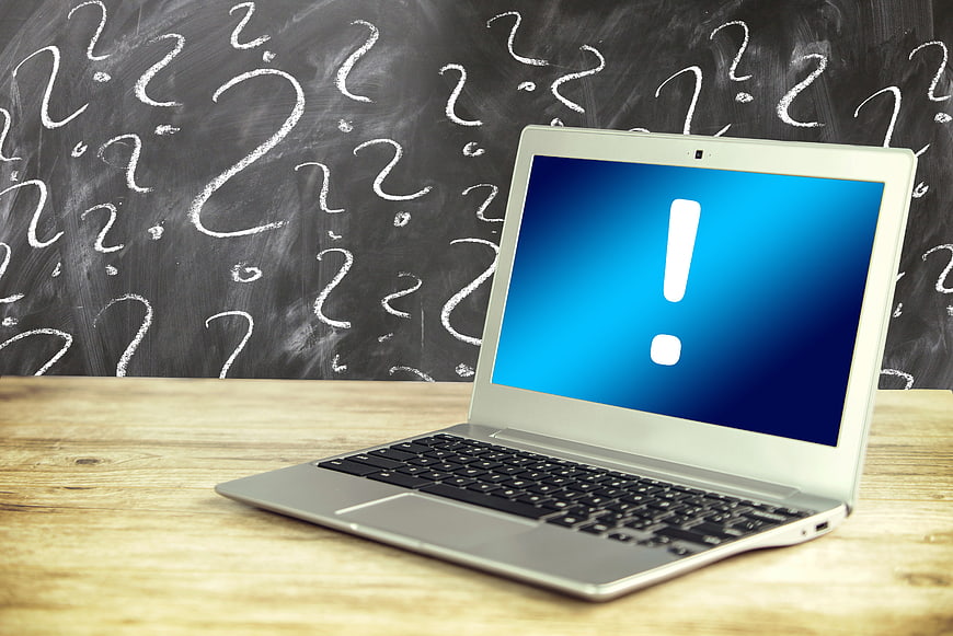 Laptop with Exclamation Mark on Blue Screen Against Chalkboard