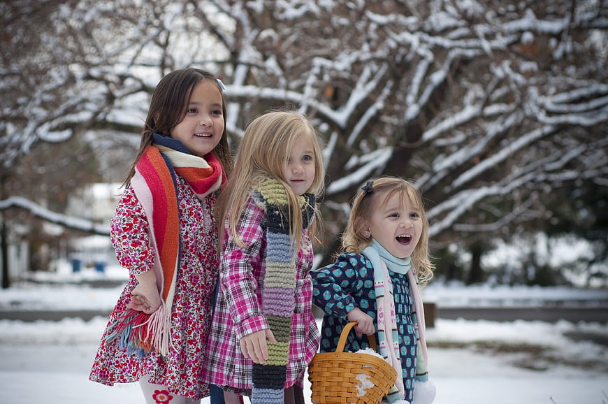 Three young girls playing in the snow with a basket