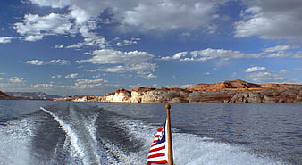 Boat Wake on Lake Powell with American Flag and Red Rock Cliffs