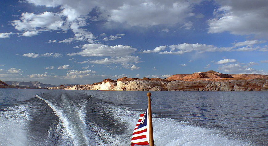 Boat Wake on Lake Powell with American Flag and Red Rock Cliffs