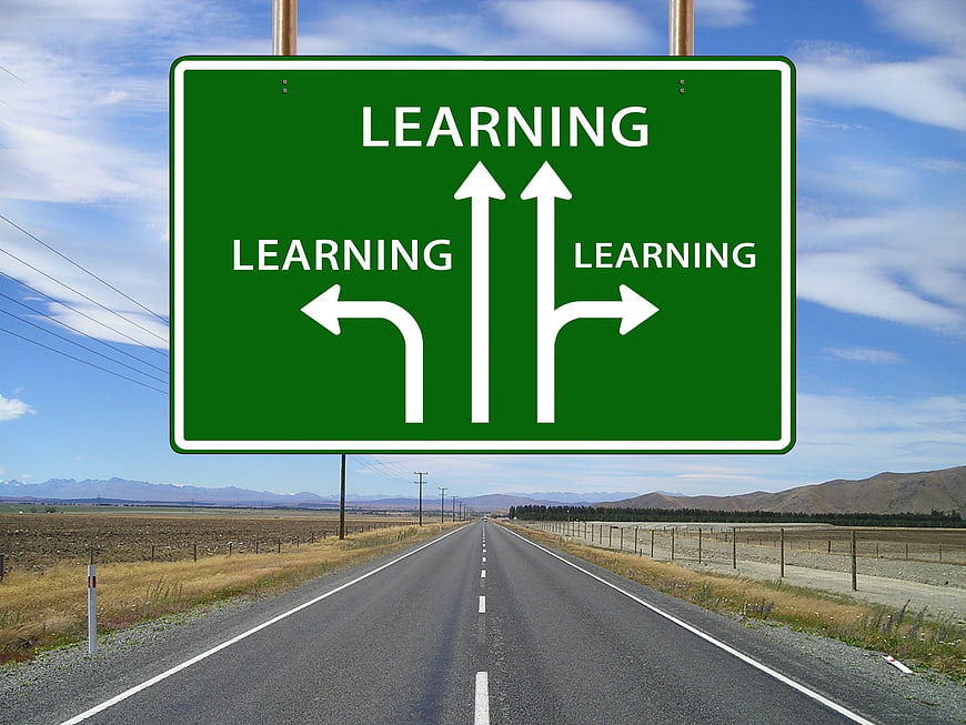 Green road sign with learning arrows on highway