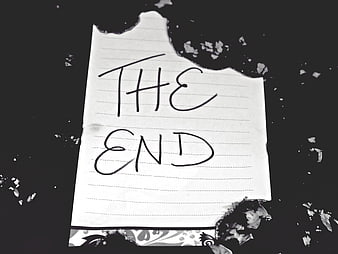 Burned paper note with handwritten text the end