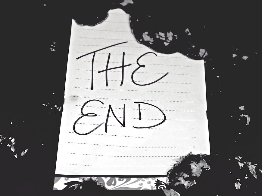 Burned paper note with handwritten text the end