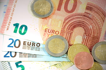 Euro banknotes and coins scattered on white background