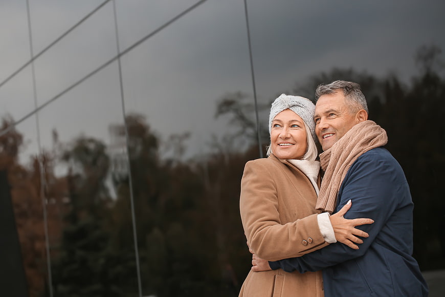 Happy Senior Couple Embracing in Front of Glass Building