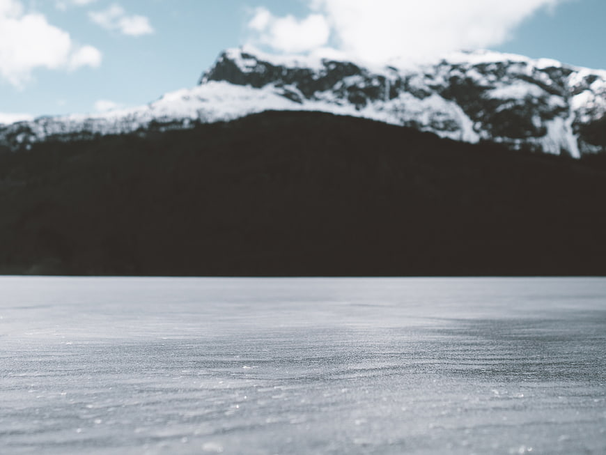 Frozen Lake Surface with Snowy Mountain Background