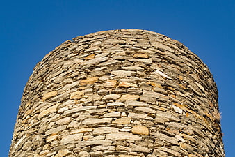 Low angle view of ancient stone tower against blue sky