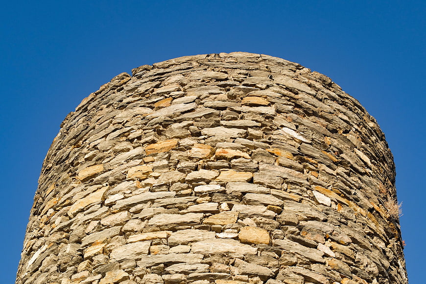 Low angle view of ancient stone tower against blue sky