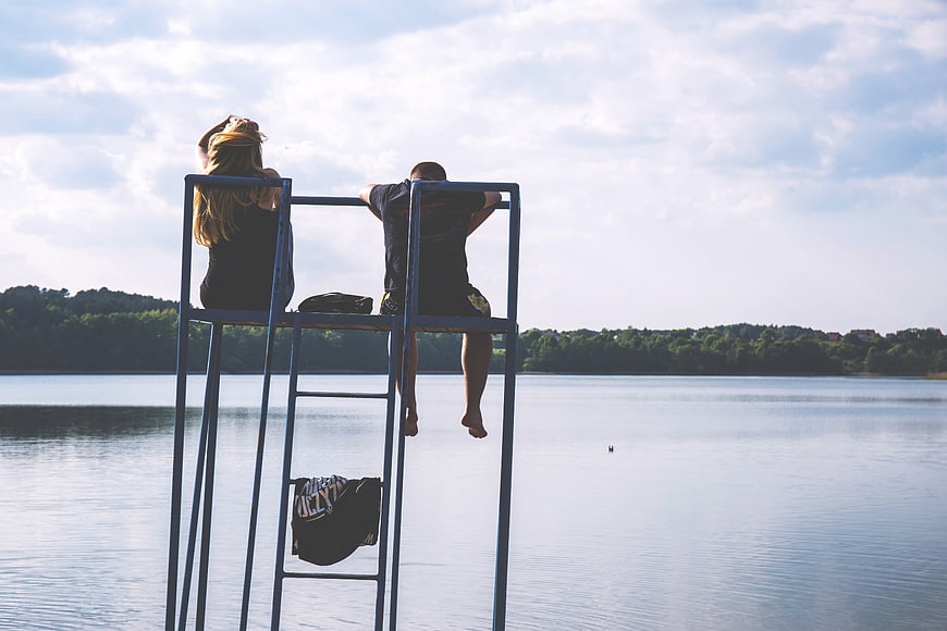 Couple sitting on lifeguard chair overlooking lake