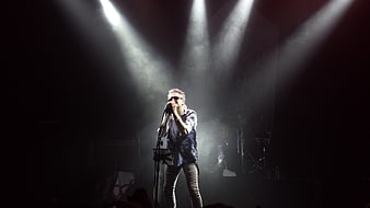 Male singer performing on stage with dramatic spotlights