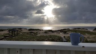 Blue Coffee Mug On Balcony Railing With Ocean Sunrise View