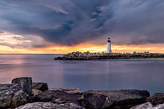 Dramatic Lighthouse on Rocky Jetty at Sunset